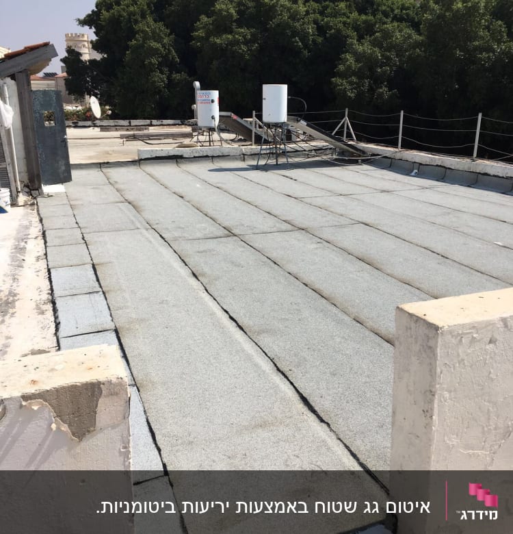 גג עם יריעות איטום אפורות ומיכלי מים